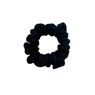 Black waffle knit cotton scrunchie with a gathered, ruffled texture, displayed against a neutral background. The ribbed fabric adds subtle dimension to the sleek black tone, offering a soft, secure hold ideal for everyday styling.