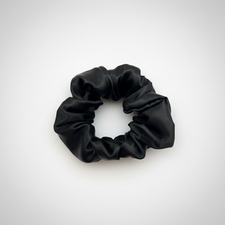Black satin scrunchie with a smooth, glossy finish, gathered into soft ruffled folds. Handmade hair accessory designed for a gentle, secure hold and a sleek, timeless look.