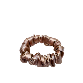 Champagne satin scrunchie with a soft rose‑golden hue and lustrous sheen, gathered into gentle ruffled folds. Handmade hair accessory designed for a secure yet gentle hold, adding a touch of radiant elegance to any style.
