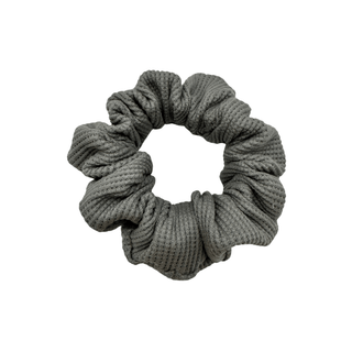 One grey waffle knit cotton scrunchie on a white background. Perfect for thick to medium hair, this scrunchie adds a touch of cozy soft elegance to any look.
