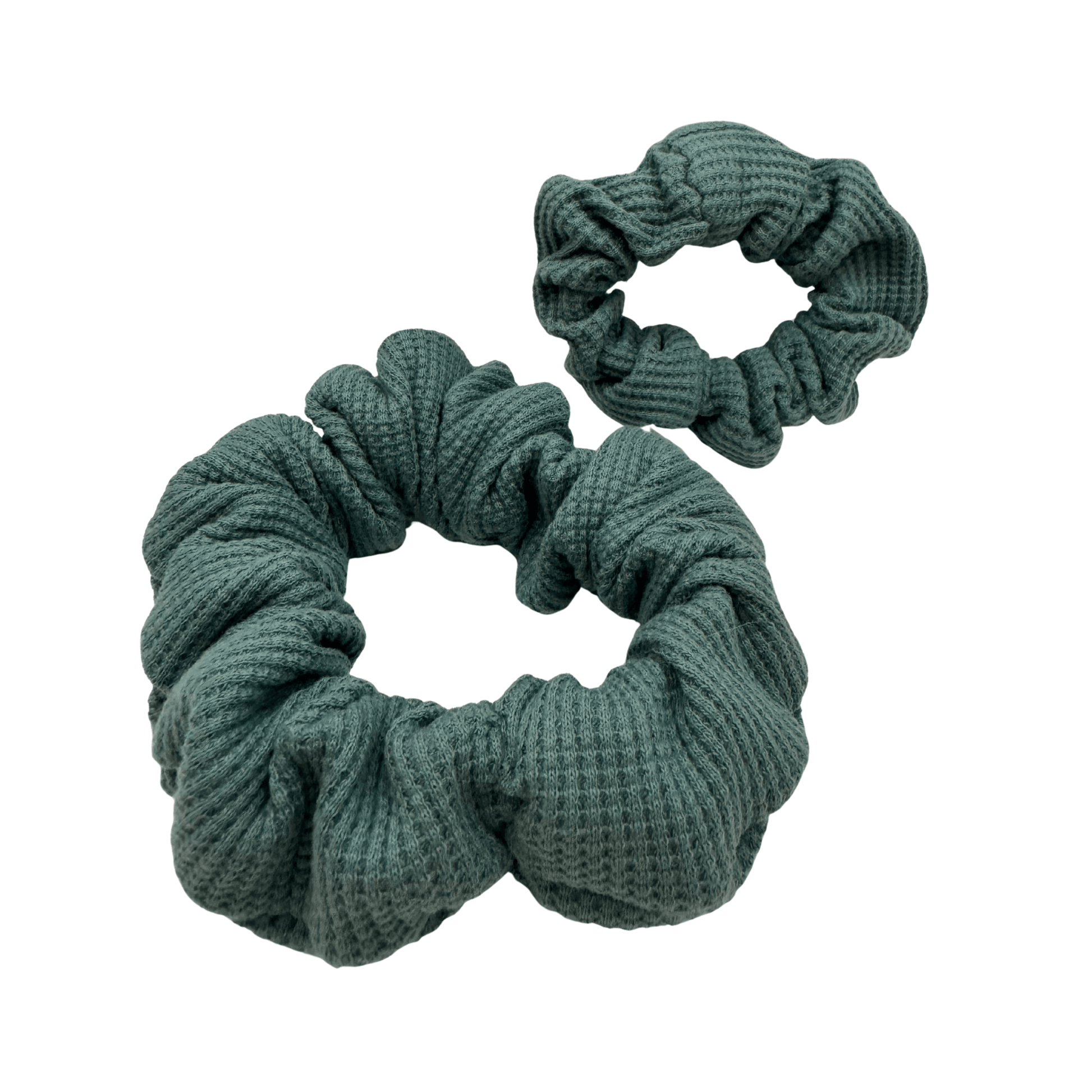 Teal waffle-knit scrunchie made from textured cotton fabric, arranged in a circular shape against a neutral background. The gathered, ribbed material creates soft volume and a cozy, tactile look