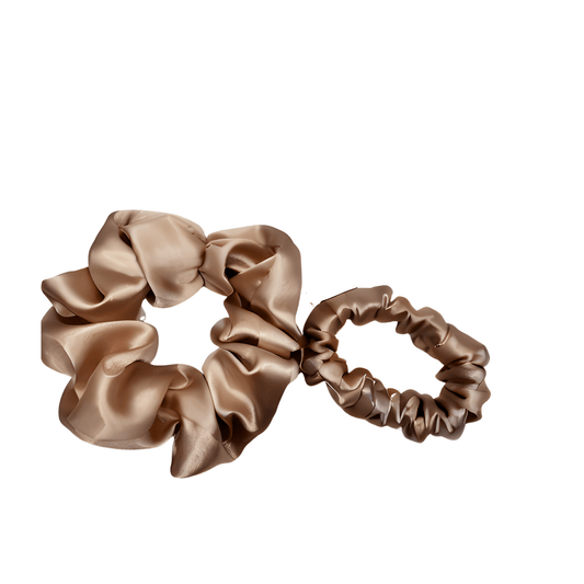 Two Champagne satin scrunchies with a soft rose‑golden hue and lustrous sheen, gathered into gentle ruffled folds. Handmade hair accessory designed for a secure yet gentle hold, adding a touch of radiant elegance to any style.