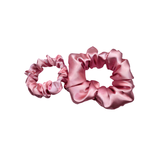 Two Baby pink satin scrunchies with a smooth, lustrous finish, arranged in soft ruffled folds. Handmade accessory designed for a gentle, secure hold and a timeless, elegant look.